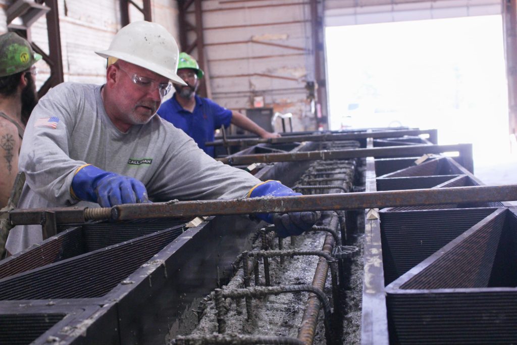 Worker prepares 3D printed latticework for concrete mixture placement