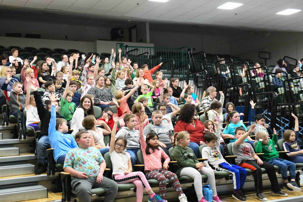 Students at Schenck High school in bleachers raising their hands