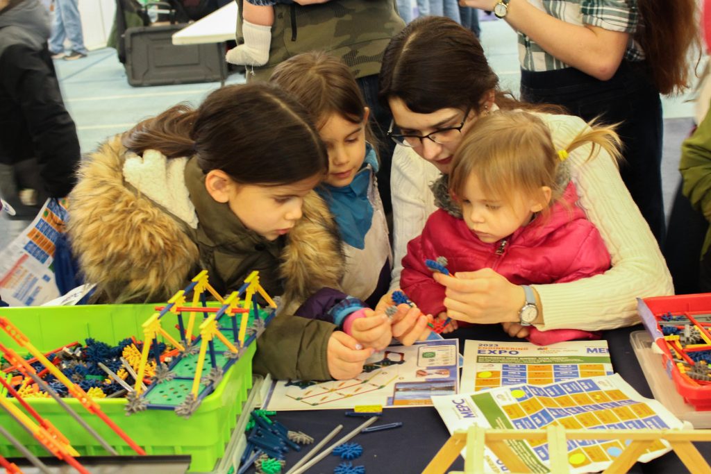 4 siblings of various ages concentrate on building a model bridge