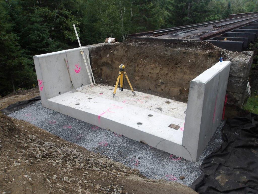 The railroad ballast retainer is set in place at the end of a railroad bridge