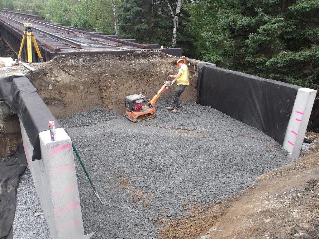 Worker used for scale inside the tub like shape of the railroad ballast retainers, the peak reaches the worker's shoulders 